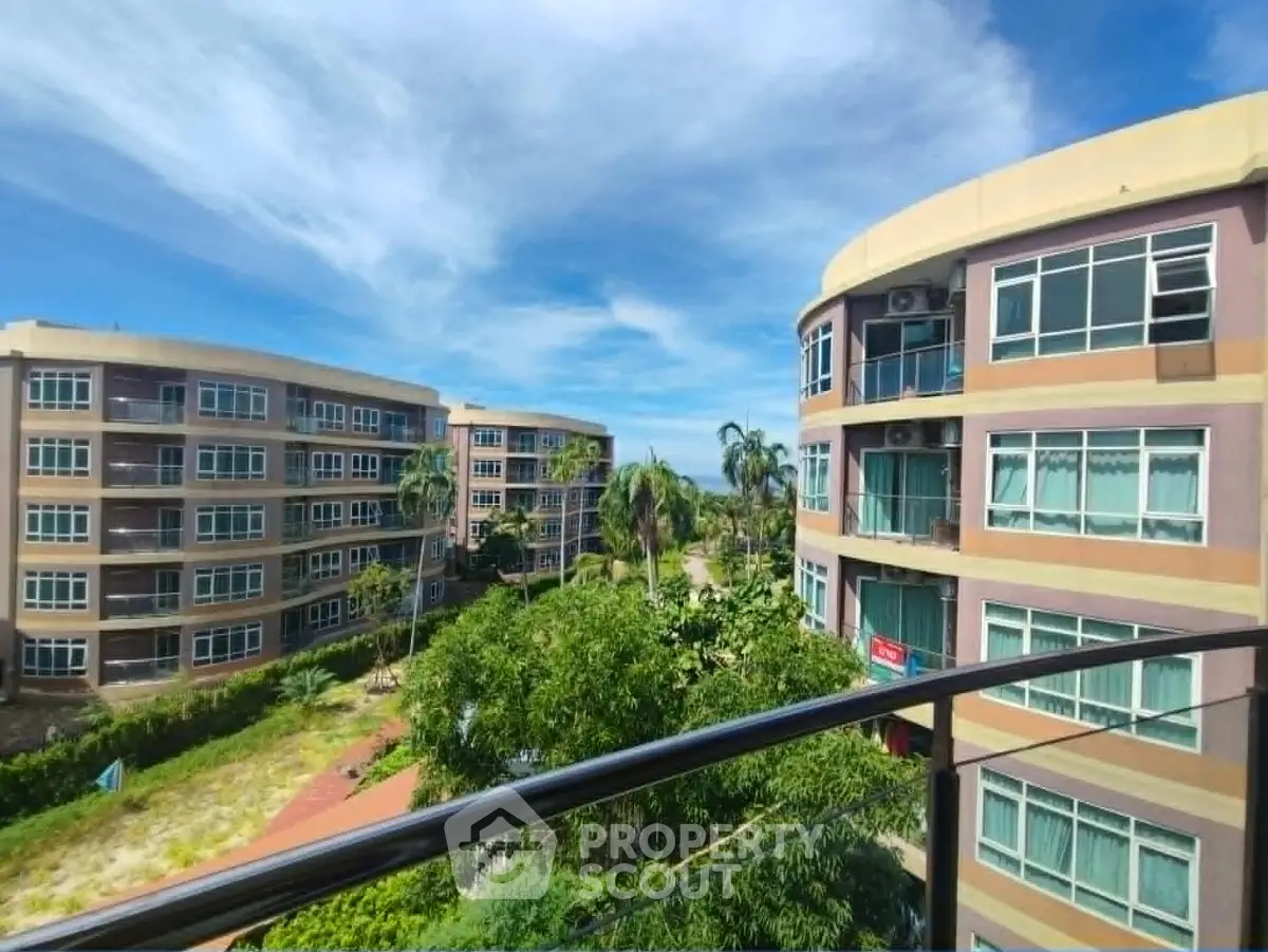 Stunning view from balcony overlooking modern apartment buildings and lush greenery.