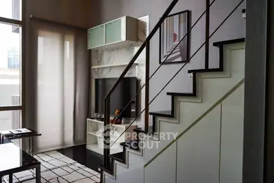 Modern living room with stylish staircase and sleek entertainment center