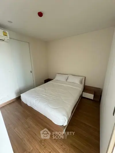 Cozy bedroom with wooden flooring and minimalist design in modern apartment.