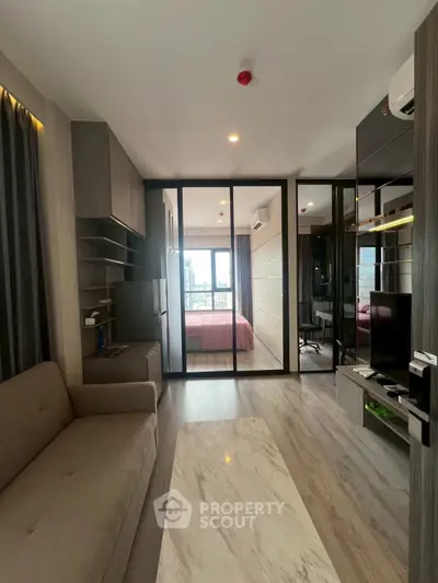 Modern apartment interior with open living room and bedroom, featuring sleek design and city view.