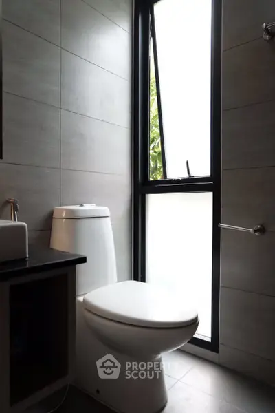 Modern bathroom with sleek design and natural light through large window.