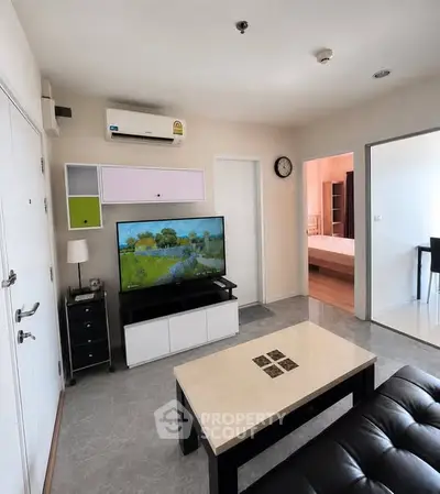 Modern living room with sleek furniture and wall-mounted TV in a cozy apartment setting.