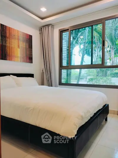 Cozy bedroom with large window and modern decor in a serene setting.