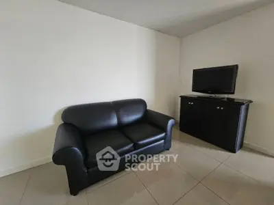 Minimalist living room with black leather sofa and TV on cabinet, perfect for cozy relaxation.