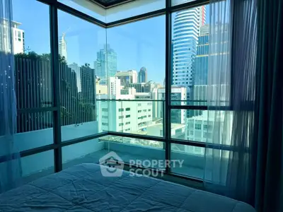 Luxurious bedroom with stunning city view and floor-to-ceiling windows in modern high-rise apartment.