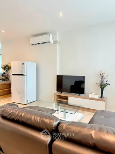Modern living room with sleek furniture and air conditioning, featuring a stylish TV setup and elegant decor.