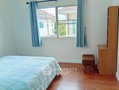 Bright bedroom with wooden flooring and large window offering natural light.