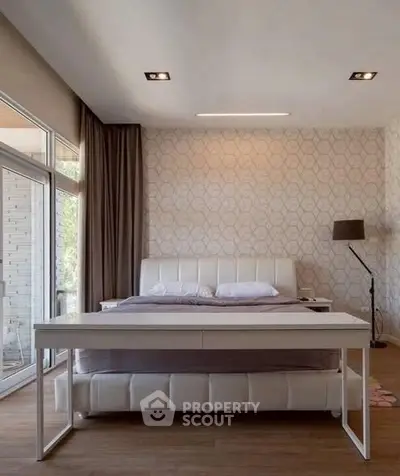 Spacious bedroom with modern decor and large windows for natural light.