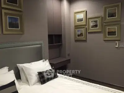 Elegant bedroom with stylish decor and framed artwork, featuring a cozy bed and modern design elements.