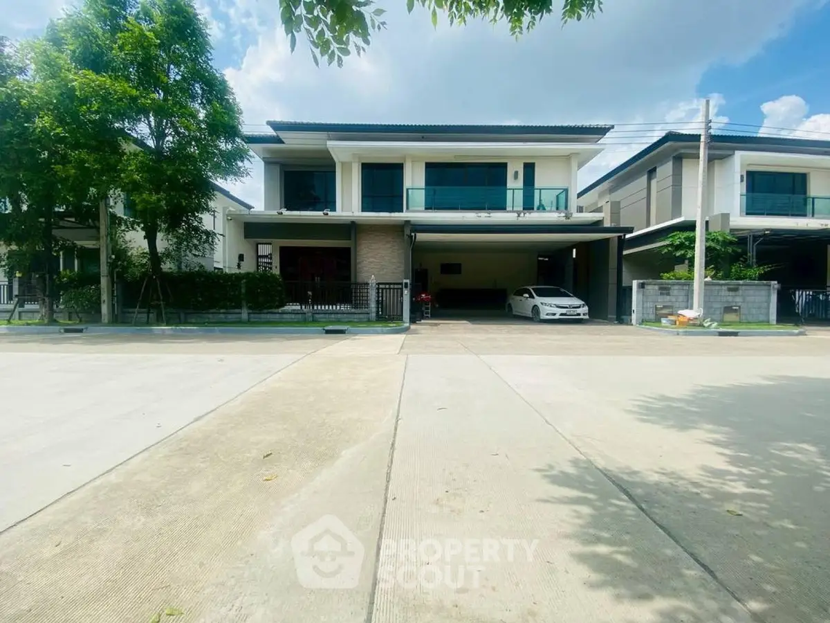 Modern two-story house with spacious driveway and lush greenery in a serene neighborhood.