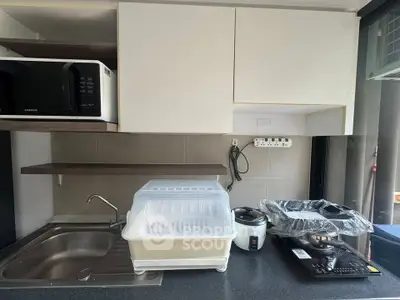 Modern kitchen with sleek appliances and ample counter space, featuring a microwave, rice cooker, and induction stove.