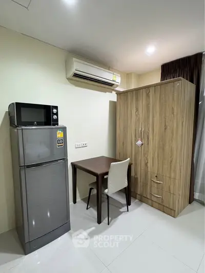 Modern apartment interior with fridge, microwave, and wooden wardrobe in a cozy corner setup.