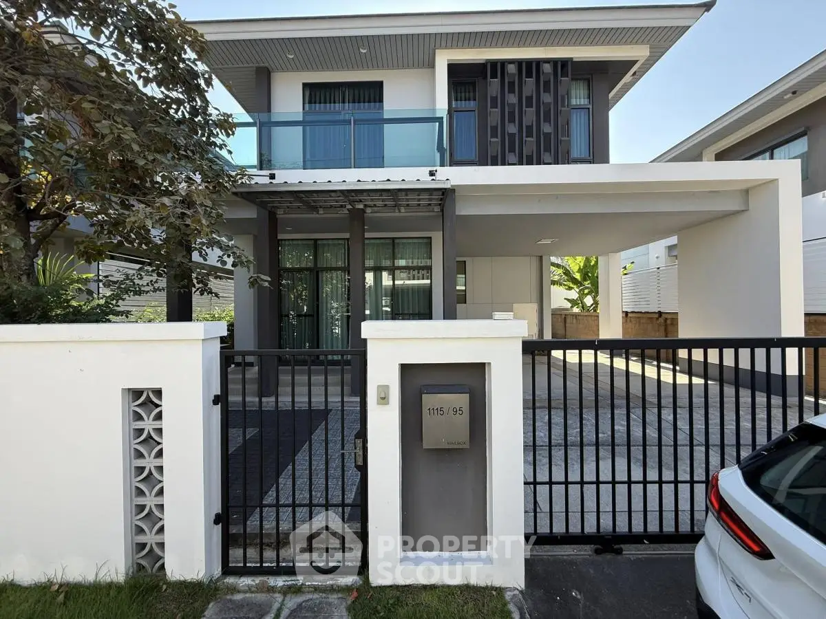Modern two-story house with gated entrance and sleek architectural design.