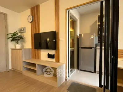 Modern living room with wall-mounted TV and view into sleek kitchen