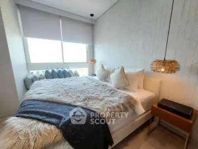 Cozy bedroom with stylish decor and large window offering natural light