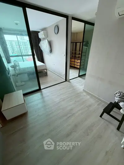 Modern bedroom with sliding glass doors and wooden flooring in a stylish apartment.