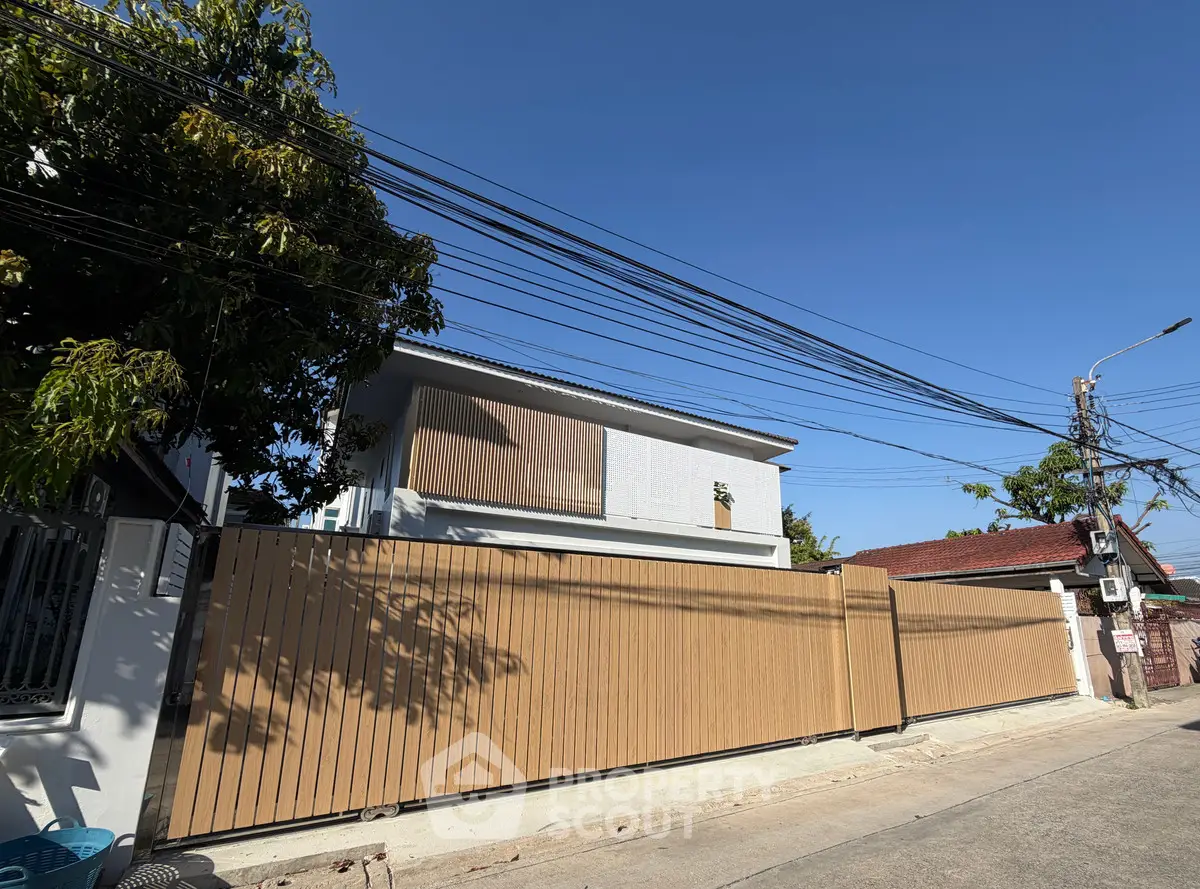 Modern two-story house with wooden fence and clear blue sky