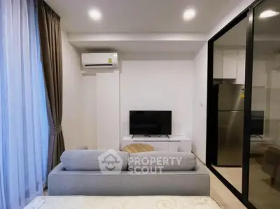 Modern living room with sleek design, featuring a cozy sofa, flat-screen TV, and large window for natural light.