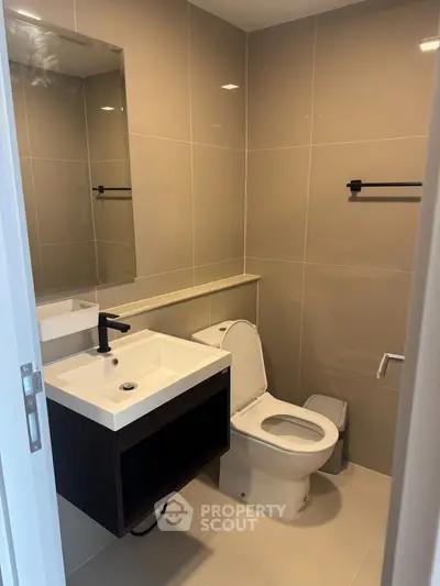 Modern bathroom with sleek fixtures and neutral tiles, featuring a stylish vanity and toilet.