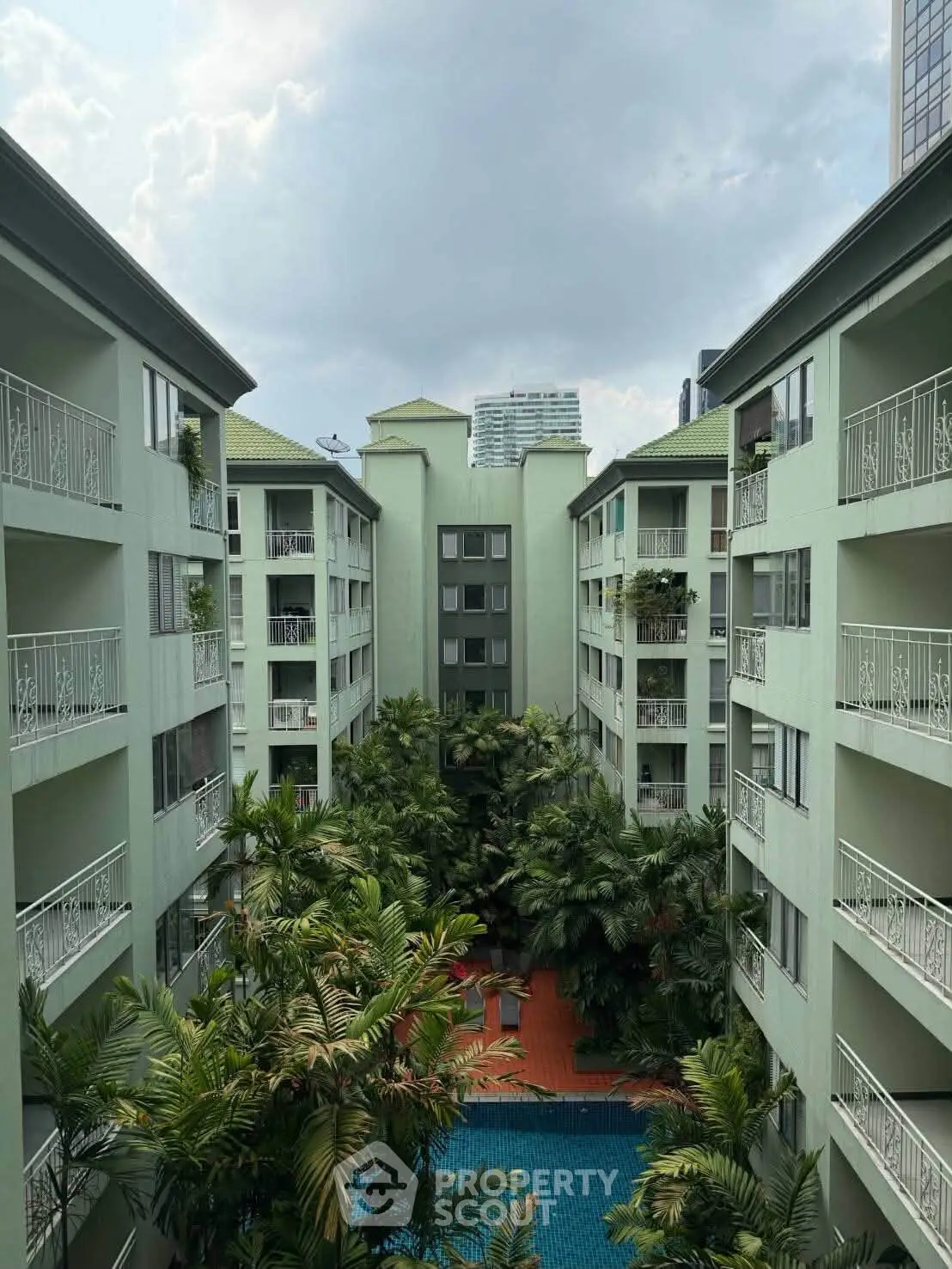 Stunning view of a modern apartment complex with lush greenery and a sparkling pool.