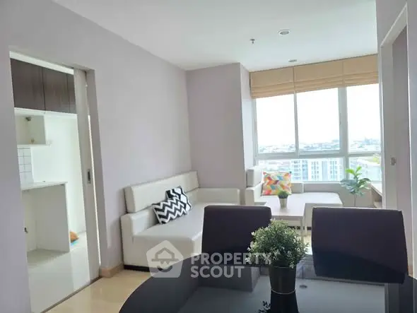 Bright and modern living room with large windows and stylish furniture in a high-rise apartment.