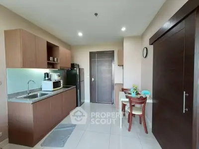 Modern kitchen with sleek cabinetry and dining area in cozy apartment.