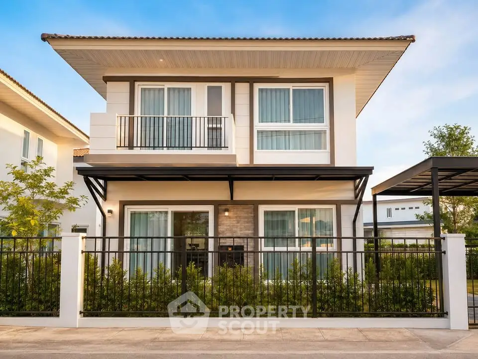 Modern two-story house with sleek design and balcony, surrounded by lush greenery and secure fencing.