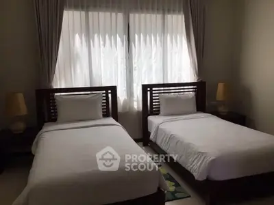 Cozy twin bedroom with natural light and elegant decor, perfect for relaxation and comfort.