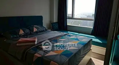 Cozy bedroom with modern decor and large window offering city view.