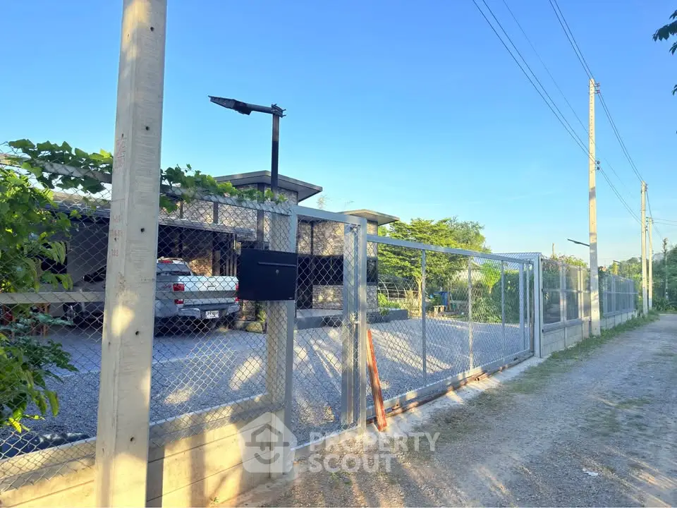 Modern gated property with spacious driveway and lush greenery