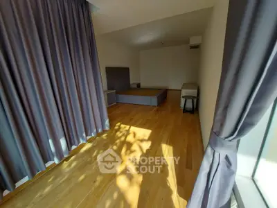 Spacious bedroom with wooden flooring and large windows for natural light.