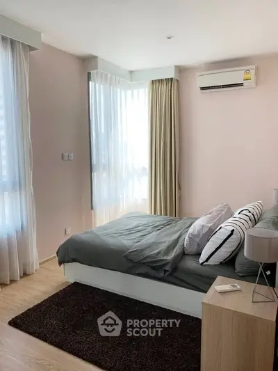 Modern bedroom with natural light, stylish decor, and air conditioning in a cozy apartment.