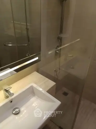 Modern bathroom with sleek fixtures and glass shower enclosure.