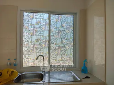 Charming kitchen with floral patterned window and modern sink, perfect for a cozy home.