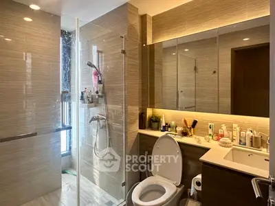 Modern bathroom with glass shower and sleek vanity in luxury apartment.