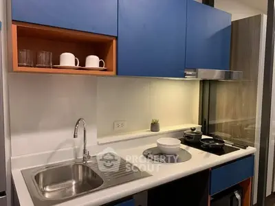 Modern compact kitchen with blue cabinets and sleek appliances