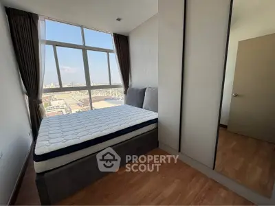 Spacious bedroom with large window offering stunning city views, featuring a comfortable bed and sleek wardrobe.