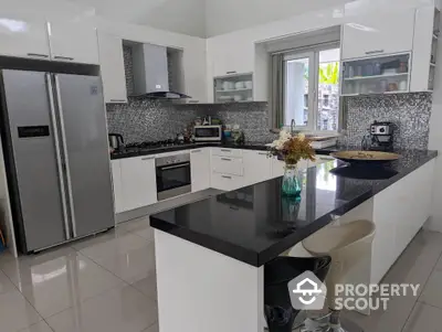 Modern kitchen with sleek black countertops, stainless steel appliances, and mosaic backsplash, perfect for culinary enthusiasts.