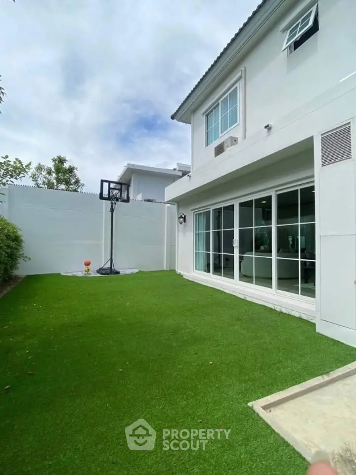 Modern home with lush green lawn and basketball hoop in backyard