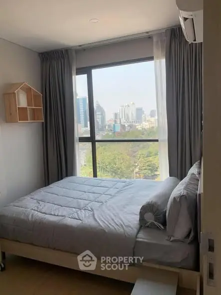 Cozy bedroom with city view and modern decor in high-rise apartment.
