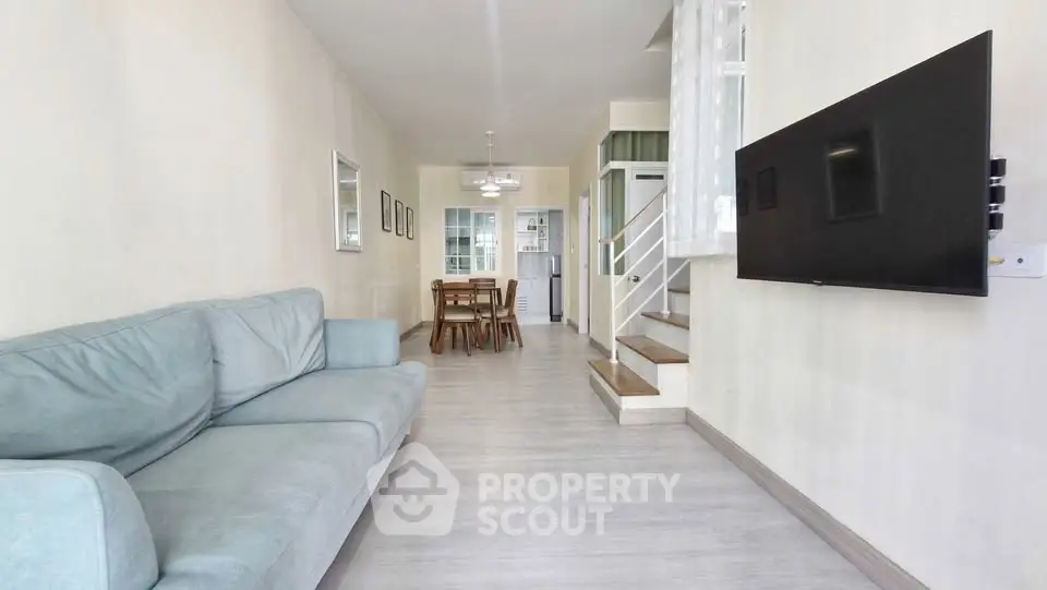 Spacious living room with modern decor and wall-mounted TV in a stylish apartment.