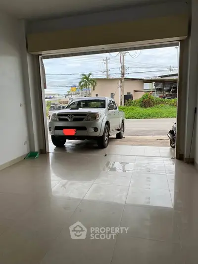 Spacious garage with tiled flooring and open view to the street, perfect for parking or storage.