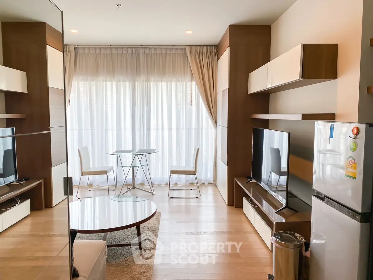 Modern living room with stylish furniture and natural light, featuring a cozy seating area and entertainment setup.