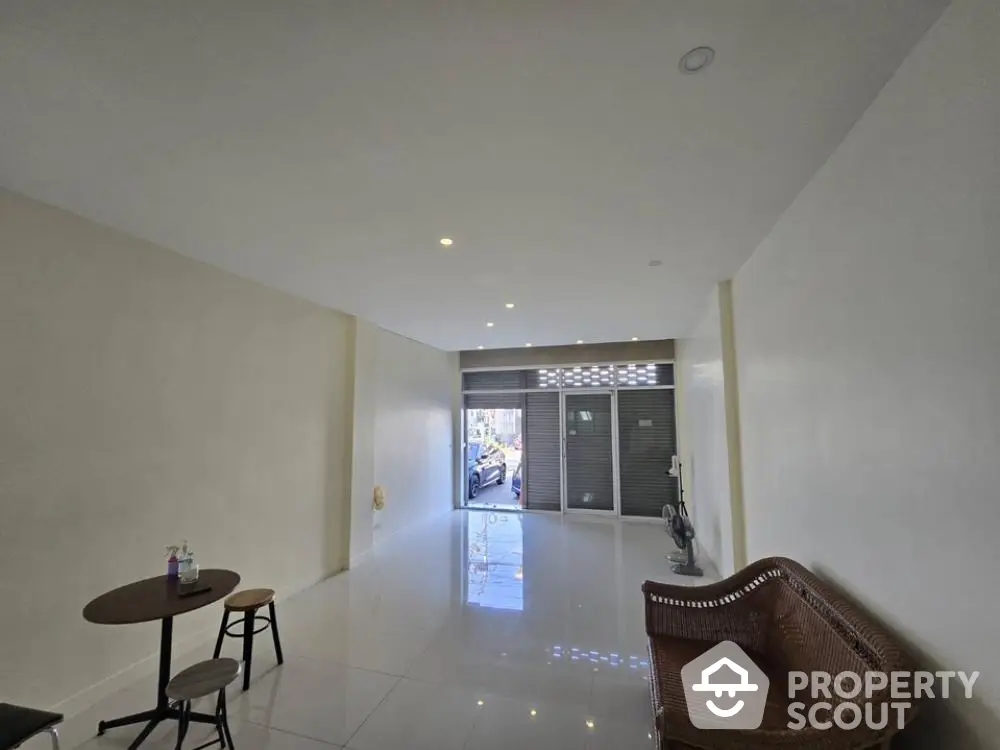 Spacious and bright living area with glossy tiled floors, leading to a welcoming entrance, perfect for modern living.