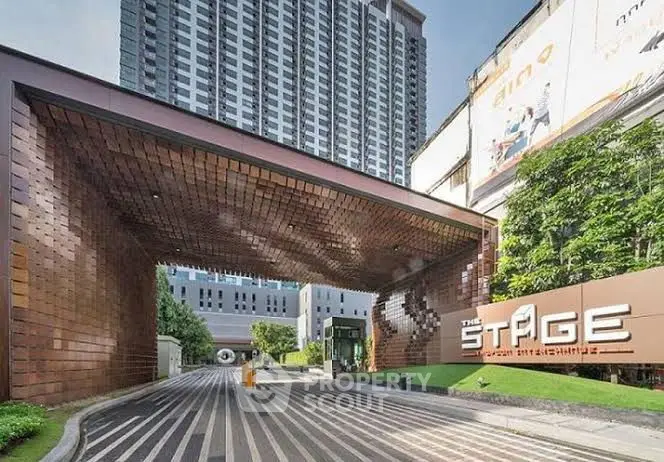 Modern building entrance with unique architectural design and high-rise backdrop.