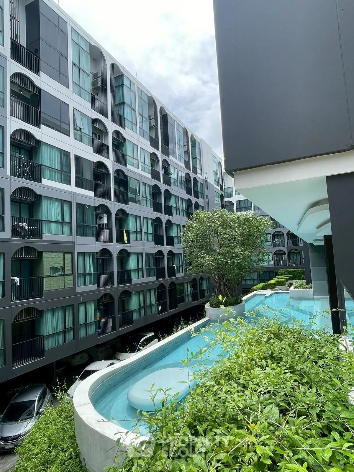 Modern apartment building with unique pool and lush greenery