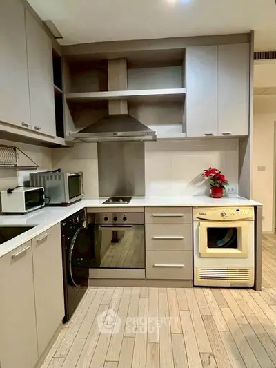 Modern kitchen with sleek cabinetry, built-in oven, and washing machine, perfect for urban living.