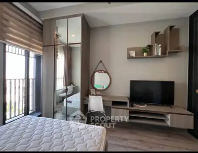 Modern bedroom with stylish furniture and natural light, featuring a cozy bed and sleek TV setup.