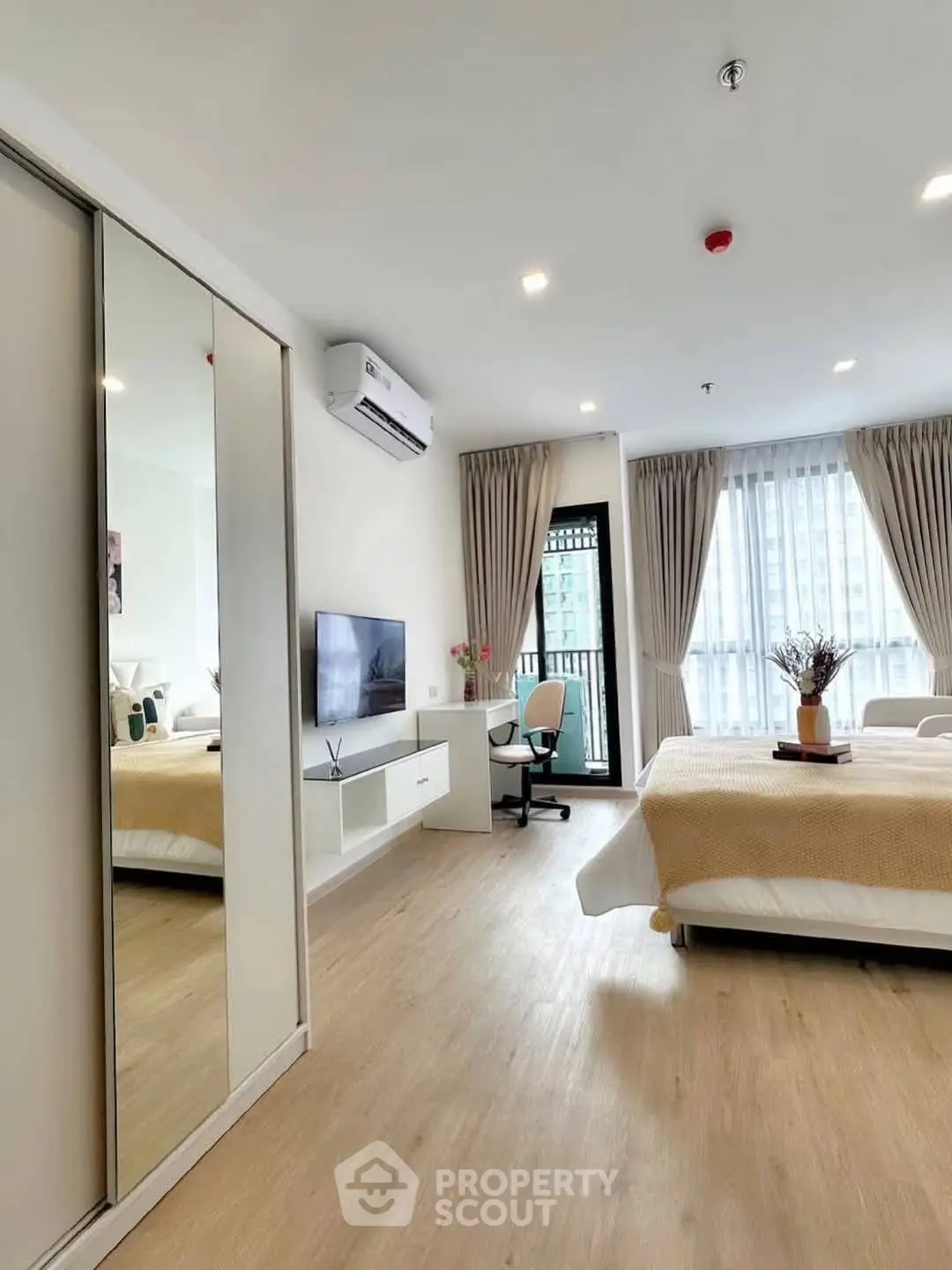 Spacious modern bedroom with large windows and stylish decor in a high-rise apartment.