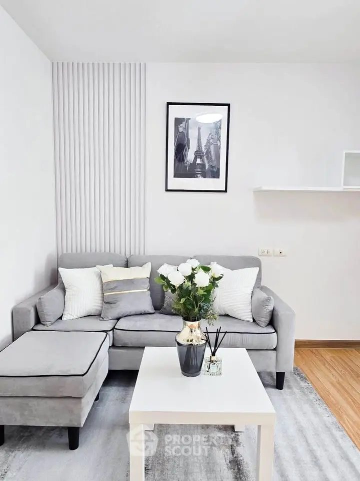 Modern living room with gray sofa, stylish decor, and elegant wall art in a cozy apartment.